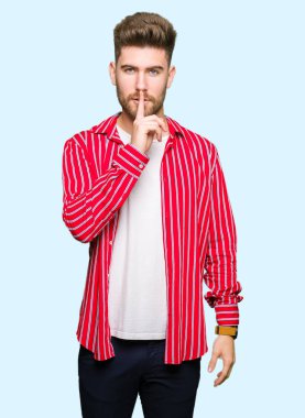 Dudaklarında parmak ile sessiz olmanı kırmızı gömlek giymiş yakışıklı delikanlı. Sessizlik ve gizli kavramı.