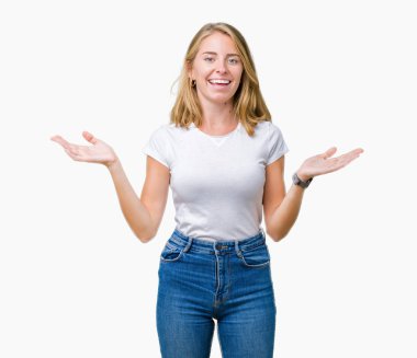 Gülen iki elle gösterilen açık avuç içi, sunma ve karşılaştırma ve denge reklam arka plan üzerinde rahat beyaz t-shirt giyen güzel ve genç birbayan izole