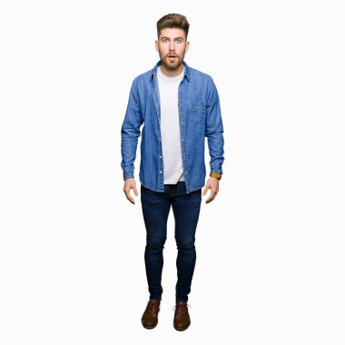 Genç yakışıklı sarışın adam rahat denim ceket korkuyor ve sürpriz ifade, korku ve heyecan yüz ile şok.