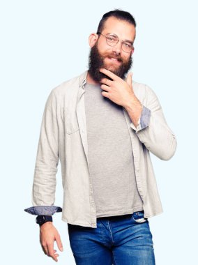 Genç sarışın adam gözlüklü emin çapraz kollar ve çeneme kaldırdı el ile gülümseme ile kameraya bakıyor. Pozitif düşünce.