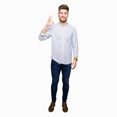 El ve parmak ile ok işareti yapıyor olumlu gülümseyen yakışıklı delikanlı. Başarılı ifade.