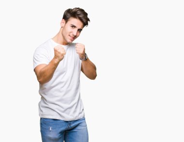 Beyaz t-shirt üzerinde izole giyen genç yakışıklı adam arka plan yumruk savunma hareketi, kızgın ve üzgün yüz, sorunu korkuyor ile savaşmaya hazır