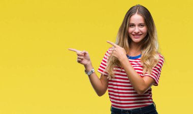 Genç güzel sarışın kadın gülümseyerek ve iki elleri ve parmakları ile tarafına işaret kamera bakarak izole arka plan üzerinde.