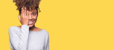 El yüz ve sürpriz duygu kendinden emin gülümseme ile tek gözüyle kapsayan izole arka plan güzel genç Afro-Amerikan kadın.