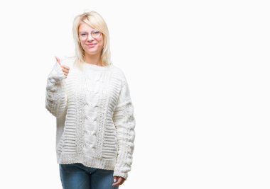 Kış kazak ve gözlük hareketi el ile mutlu yaşasın yapıyor izole arka plan üzerinde giyen genç güzel sarışın kadın. Kameraya bakarak başarı gösteren ile ifade onaylama.