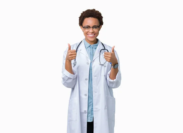 肯定的なジェスチャーを行う分離背景成功記号の上医療のコートを着ている若いアフリカ系アメリカ人医師女性の親指を笑顔と幸せ 勝者ジェスチャー晴れやかな表情でカメラを見てください — ストック写真