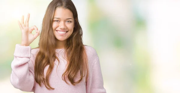 年轻美丽的黑发女人穿着粉红色的冬季毛衣在孤立的背景微笑积极做确定的迹象与手和手指 成功的表达 — 图库照片