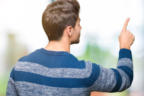 İzole genç yakışıklı adam arka plan geriye doğru arkasında parmak eliyle işaret Posing