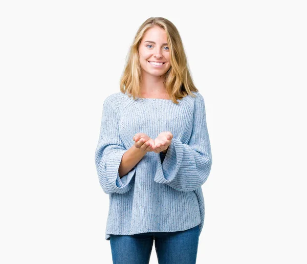 美丽的年轻女子穿着蓝色毛衣在孤立的背景微笑与手手掌一起接受或给予手势 保持和保护 — 图库照片