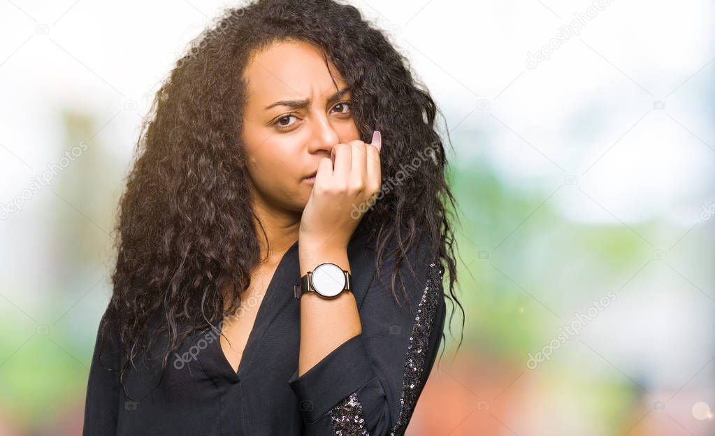 Young beautiful girl with curly hair wearing elegant dress looking stressed and nervous with hands on mouth biting nails. Anxiety problem.