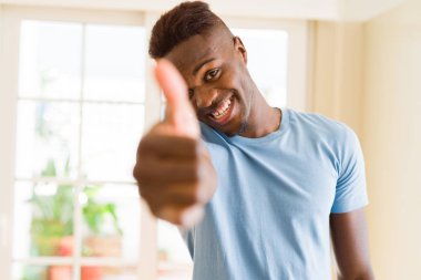 Başarı gülümseyen heyecan için başparmak yukarıya jest, büyük sembolü yapan yakışıklı Afrika genç erkek