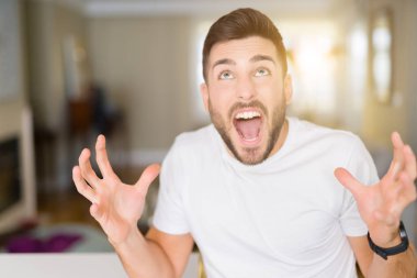 Evde çılgın ve kızgın bağırarak ve agresif ifade ve silah kaldırdı bağırmaya Casual beyaz t-shirt giyen genç yakışıklı adam. Hayal kırıklığı kavramı.