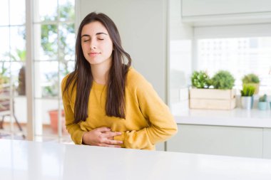 Güzel genç kadın mide el ile sarı kazak giyiyor çünkü hazımsızlık, ağrılı hastalık rahatsızlık hissi. Ağrı kavramı.