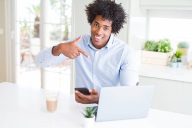 Afrika kökenli Amerikalı iş adamı smartphone ve dizüstü bilgisayar ile sürpriz kullanarak yüz kendine işaret parmağı