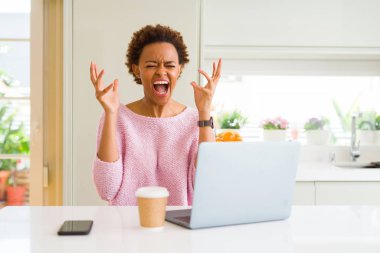 Kızgın ve başarı için deli dizüstü bilgisayar ile silah kaldırdı kutluyor ve heyecanlı çığlık kapalı gözler kullanarak çalışan genç Afro-Amerikan kadın. Kazanan kavramı