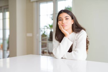 Beyaz masa düşünme görünümlü genç güzel kadın evde yorgun ve sıkılmış çapraz silah depresyon sorunları ile.