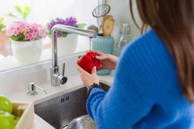 Genç kadın lavabo su kullanarak sebze ve meyve yıkama