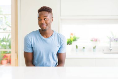 Evde rahat t-shirt giyen yakışıklı Afrikalı Amerikalı adam görünümlü yan ve düşünmek uzağa bakıyor.