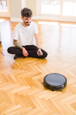 Genç adam otomatik elektrikli süpürge kullanarak zemin temizlemek için, kontrol makine ev işi robot