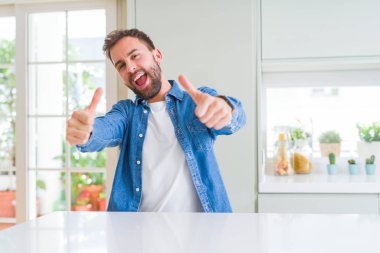 Yakışıklı adam evde el ile pozitif jest yapıyor onaylama gülümseyen ve başarı için mutlu Yaşasın. Kamera, kazanan jest arıyorsunuz.