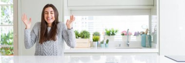 Güzel genç kadının evde beyaz masada oturan geniş açı resmi silah ile başarı için deli ve deli kutluyor ve heyecanlı çığlık kapalı gözleri kaldırdı. Kazanan kavramı