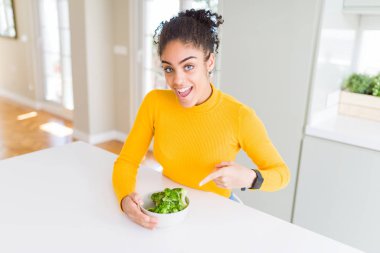 Genç African Amerikan kız yemek heatlhy yeşil brokoli çok mutlu işaret ile el ve parmak