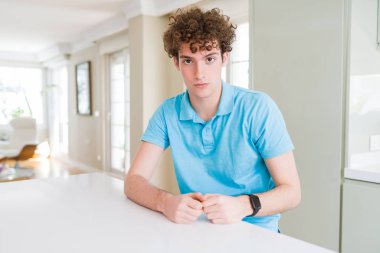 Yüzünde rahat mavi t-shirt evde ciddi ifade ile giyen genç yakışıklı adam. Basit ve doğal kameraya bakıyor.