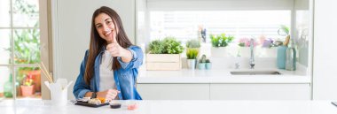 Güzel genç kadının geniş açı resmi el ile jest kadar mutlu başparmak yapıyor teslim suşi yeme. Başarı göstererek kameraya bakarak ifadeyi onaylama.