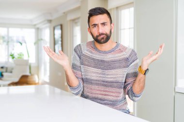 Yakışıklı İspanyol giyen sıradan kazak ev clueless ve şaşkın bir ifadeyle kollar ve eller kaldırdı, dostum. Şüphe kavramı.