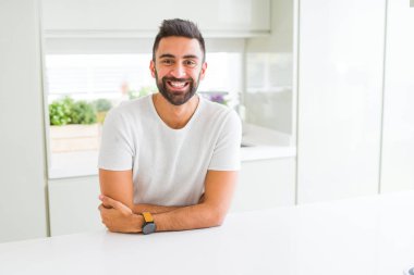 Yakışıklı İspanyol ile mutlu yüz gülümseyerek kameraya seyir silah geçti casual beyaz t-shirt evde dostum. Olumlu bir kişi.
