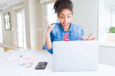 Bilgisayar laptop kullanarak genç Afrikalı Amerikan öğrenci kadın çok mutlu ve heyecanlı, kazanan ifade zafer büyük gülümseme ile çığlık kutluyor ve eller kaldırdı