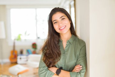 Güzel esmer kadın neşeli gülümseyen, çapraz silah ile mutlu ve olumlu görünümlü