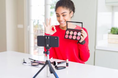 Genç Afro-Amerikan etki unsuru kadın kayıt makyaj öğretici ok işareti parmaklar, mükemmel sembolü ile yapıyor