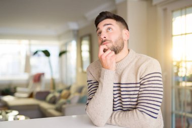 Genç yakışıklı adamla evde el çene düşünme hakkında soru, dalgın ifade üzerine. Düşünceli yüzüyle gülümsüyor. Şüphe kavramı.