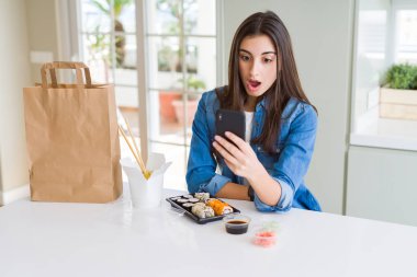 Şaşırtıcı bir yüz ile şok korkuyor akıllı telefon kullanarak uygulamadan gıda teslim sipariş güzel genç kadın, korku ve heyecanlı ifade ile heyecan