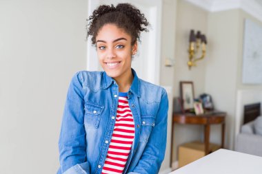 Yüzünde mutlu ve güzel bir gülümseme ile rahat denim ceket giyen afro saçlı güzel genç Afro-Amerikan kadın. Şanslı kişi.
