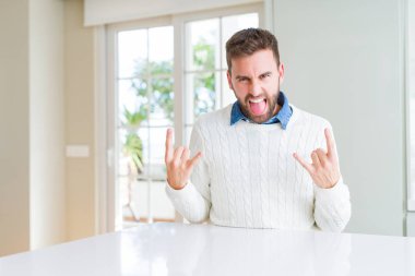 Yakışıklı adam deli ifade rock simge elle yapıyor ile rahat kazak bağırarak giyiyor. Müzik yıldızı. Ağır kavramı.