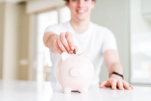 Zbliżenie na człowieka, wprowadzenie monety wewnątrz piggy bank jako oszczędności lub w — Zdjęcie stockowe