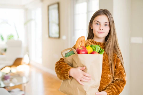 美しい女の子が新鮮な食料品の紙袋を持っている スマートな顔に自信を持って表現する真剣な考え — ストック写真