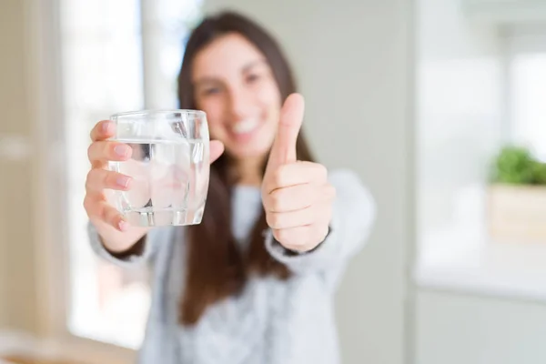 大きな笑顔で幸せな水の新鮮なガラスを飲んでいる美しい若い女性 サインをして 指で親指を 優れた兆候 — ストック写真