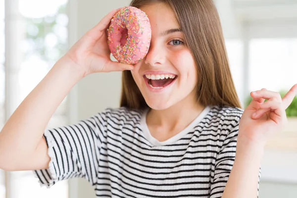 美丽的年轻女孩女孩吃甜粉红色甜甜圈非常高兴用手和手指指向一边 — 图库照片