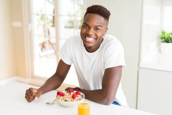 Handsome african american man eating heatlhy cereals and berries as breakfast