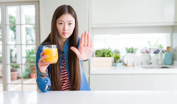 美丽的亚洲女人喝了一杯新鲜的橙汁与开放的手做停止标志与严肃和自信的表达 防御姿态 — 图库照片
