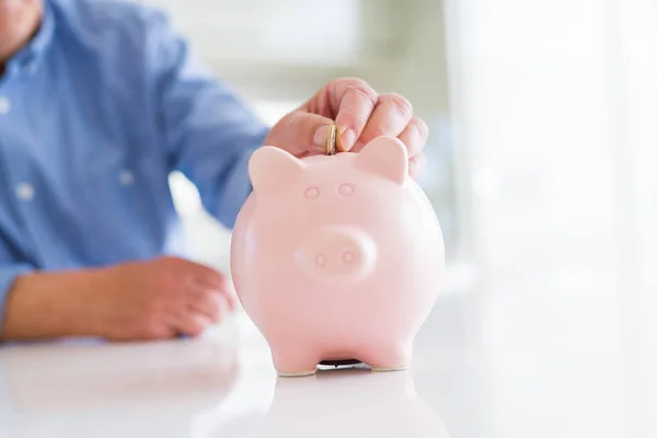 Primer plano del hombre poniendo una moneda dentro de la alcancía como ahorro — Foto de Stock