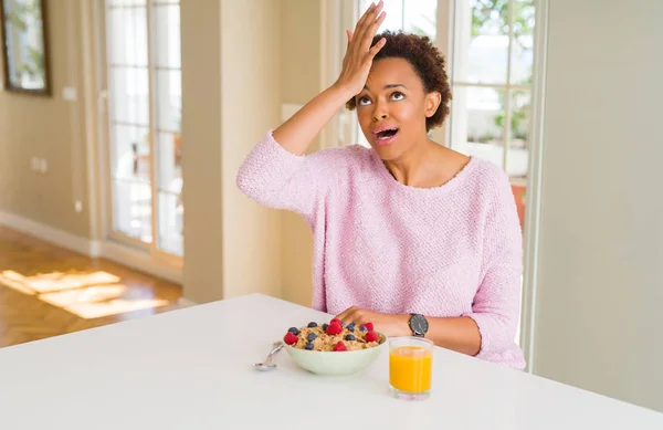 Young african american woman having healthy breakfast in the morning at home surprised with hand on head for mistake, remember error. Forgot, bad memory concept.