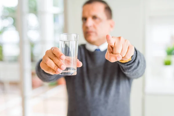 家庭での水の中年男の飲料のガラス カメラにして 指で指している手の正面からポジティブで自信のジェスチャ記号 — ストック写真