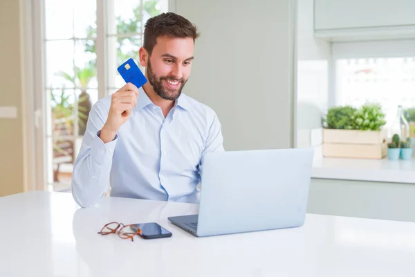 Hombre de negocios guapo compras en línea utilizando ordenador portátil y —  Fotos de Stock