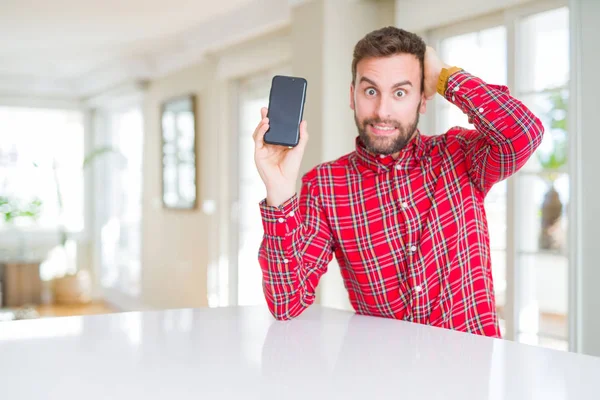 Knappe Man Toont Smartphone Scherm Benadrukt Met Hand Het Hoofd — Stockfoto