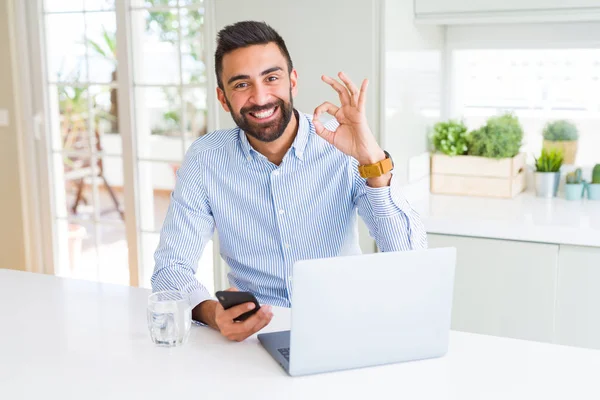 Przystojny Hiszpan Człowiek Pomocą Laptopa Smartphone Robi Znak Palcami Doskonały — Zdjęcie stockowe