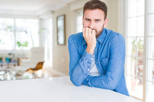 Yakışıklı adam evde stresli ve gergin elle çivi ısırma ağzına bakıyor. Anksiyete sorunu.